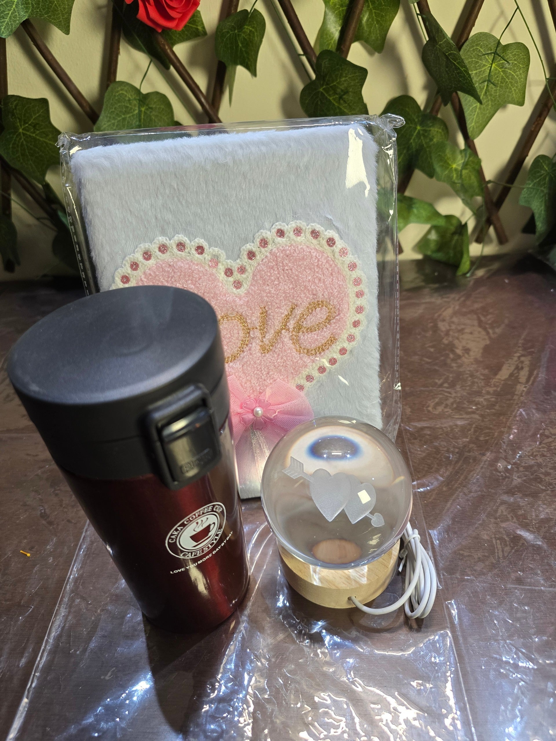 BioCode gift set including a plush heart notebook, dark red insulated travel mug, and crystal ball night light.