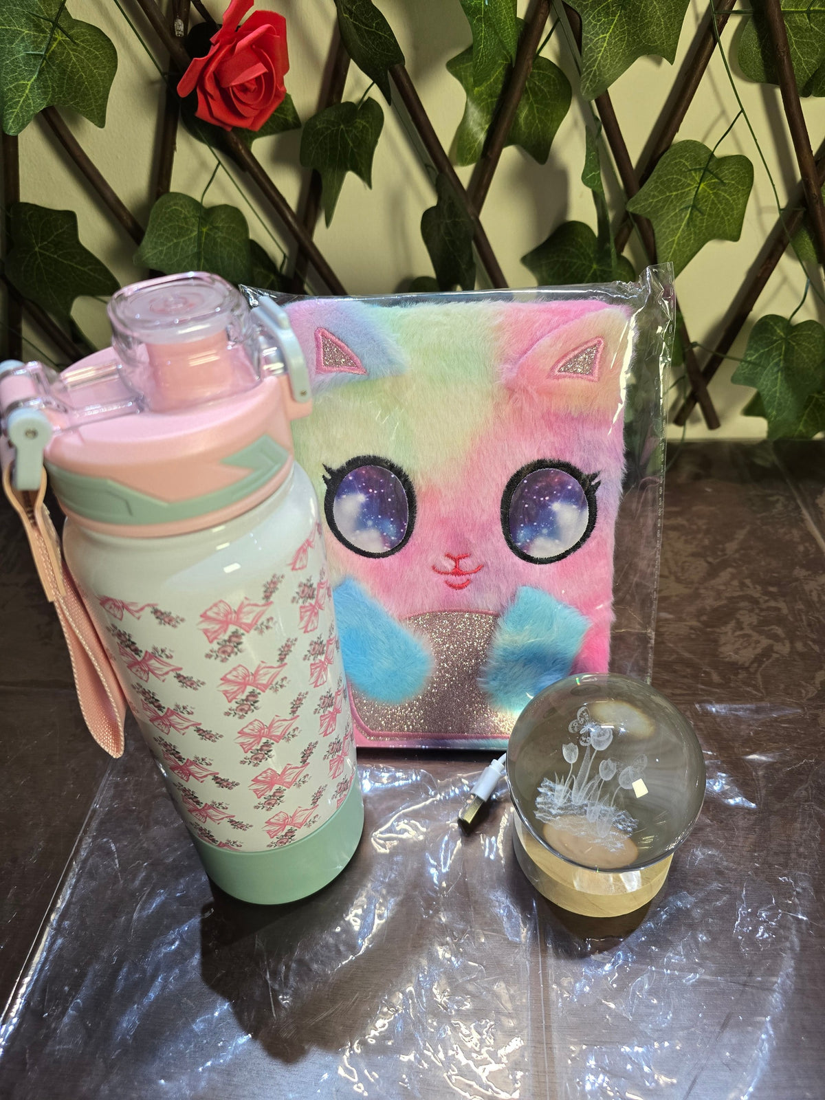 BioCode three-piece gift set featuring a plush tie-dye cat notebook, floral water bottle, and crystal LED light orb.