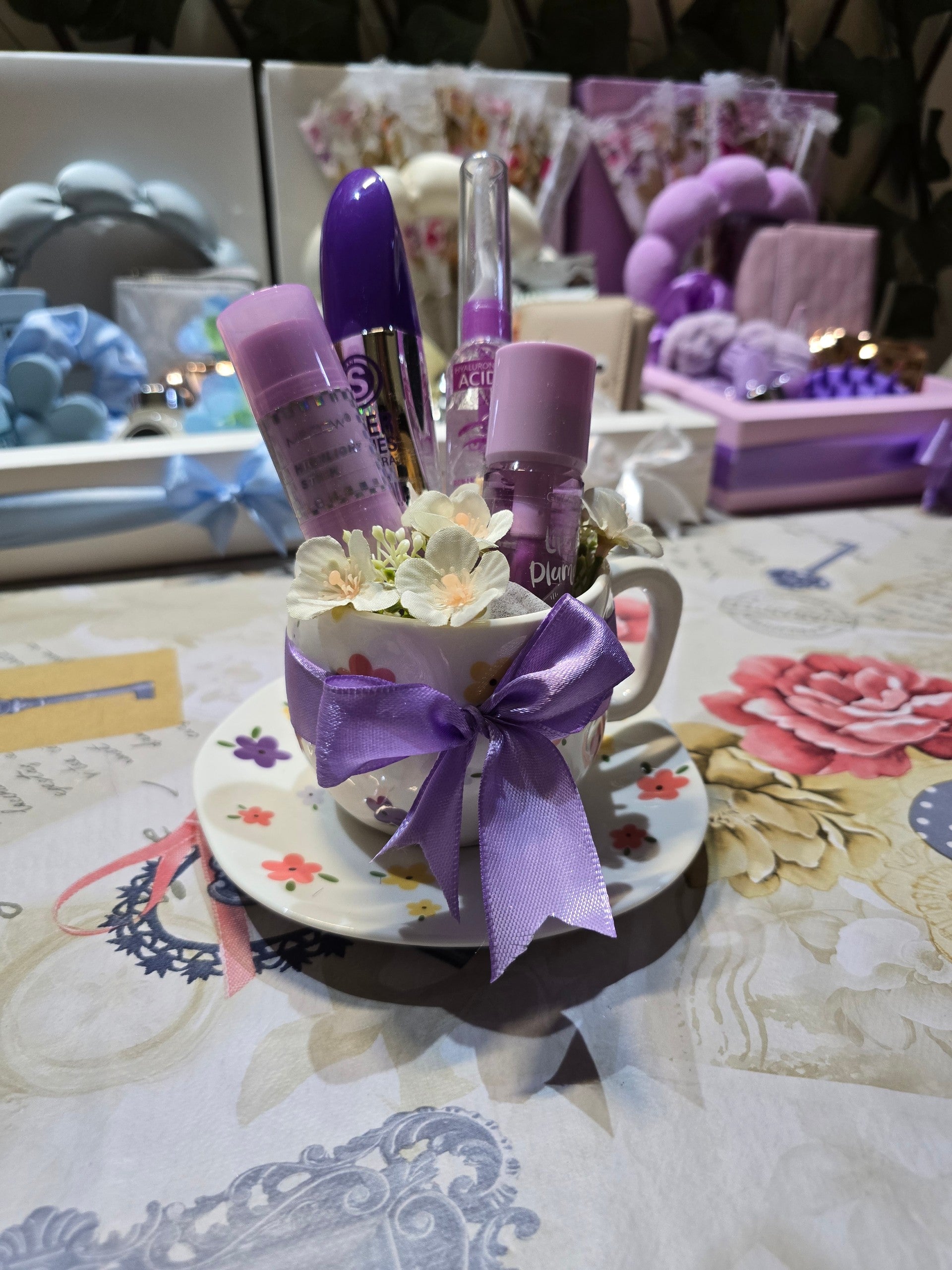 BioCode decorative teacup gift set featuring purple mascara, lash treatment, and lip plumper with floral accents.