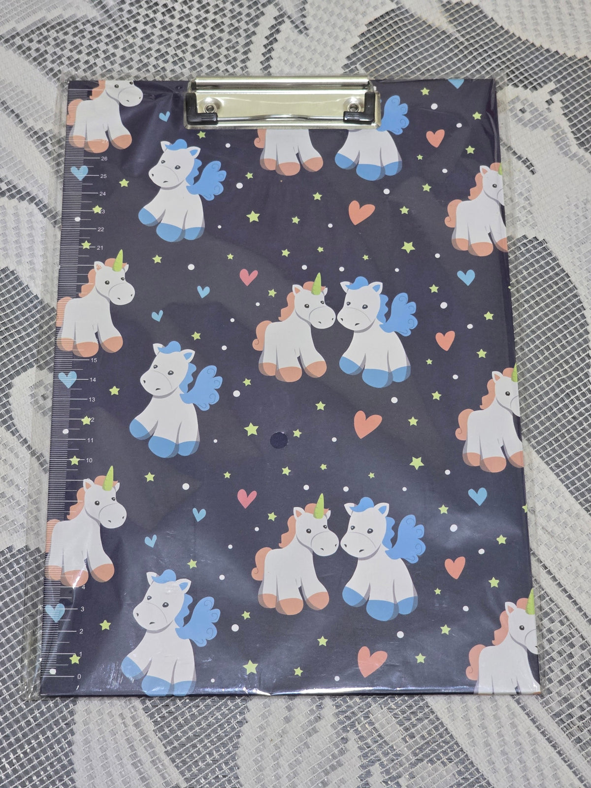 BioCode A4 clipboard featuring a dark navy background with a playful unicorn, heart, and star pattern and side ruler.