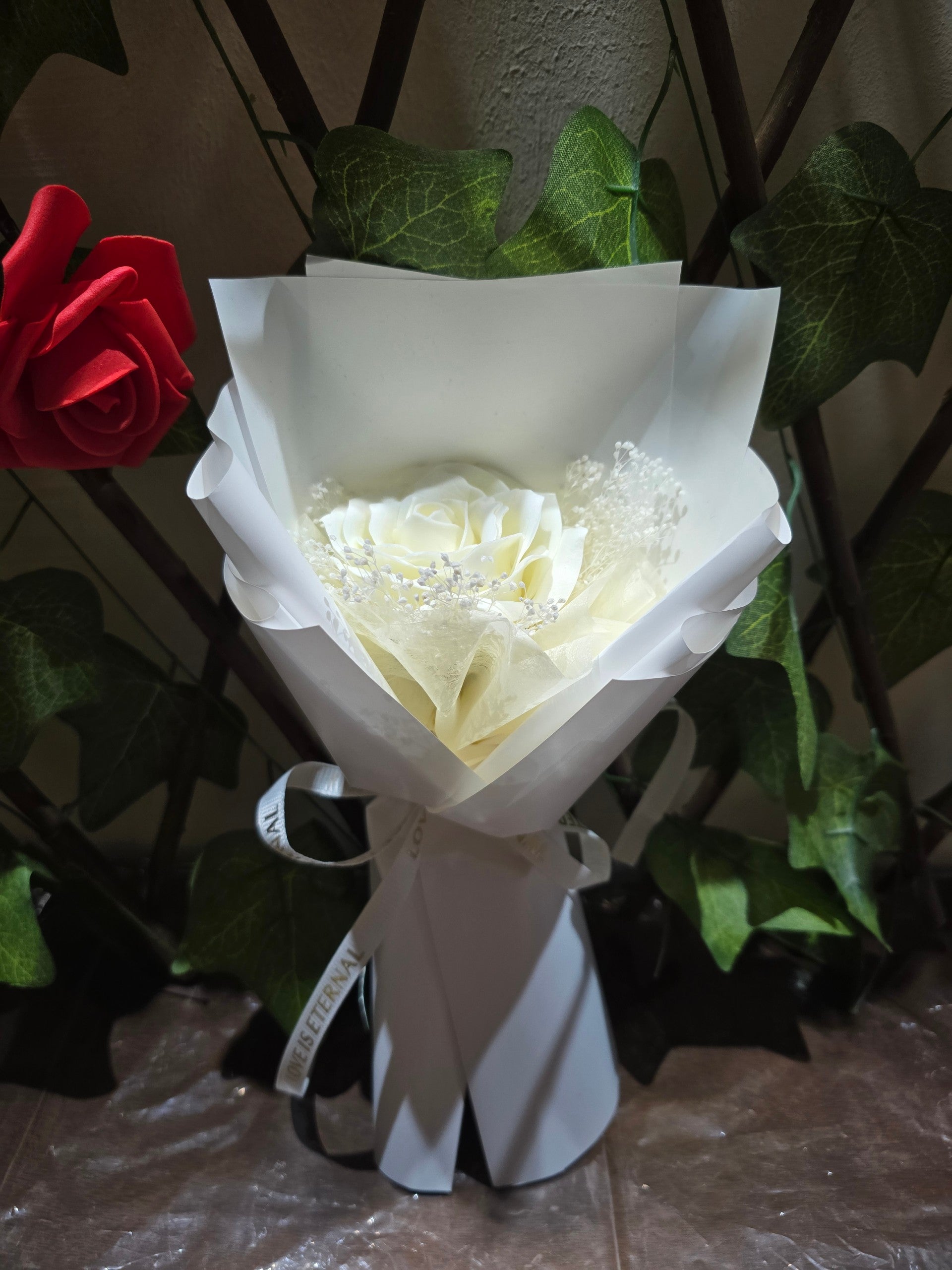BioCode white artificial eternity rose bouquet wrapped in elegant paper with baby's breath and a ribbon