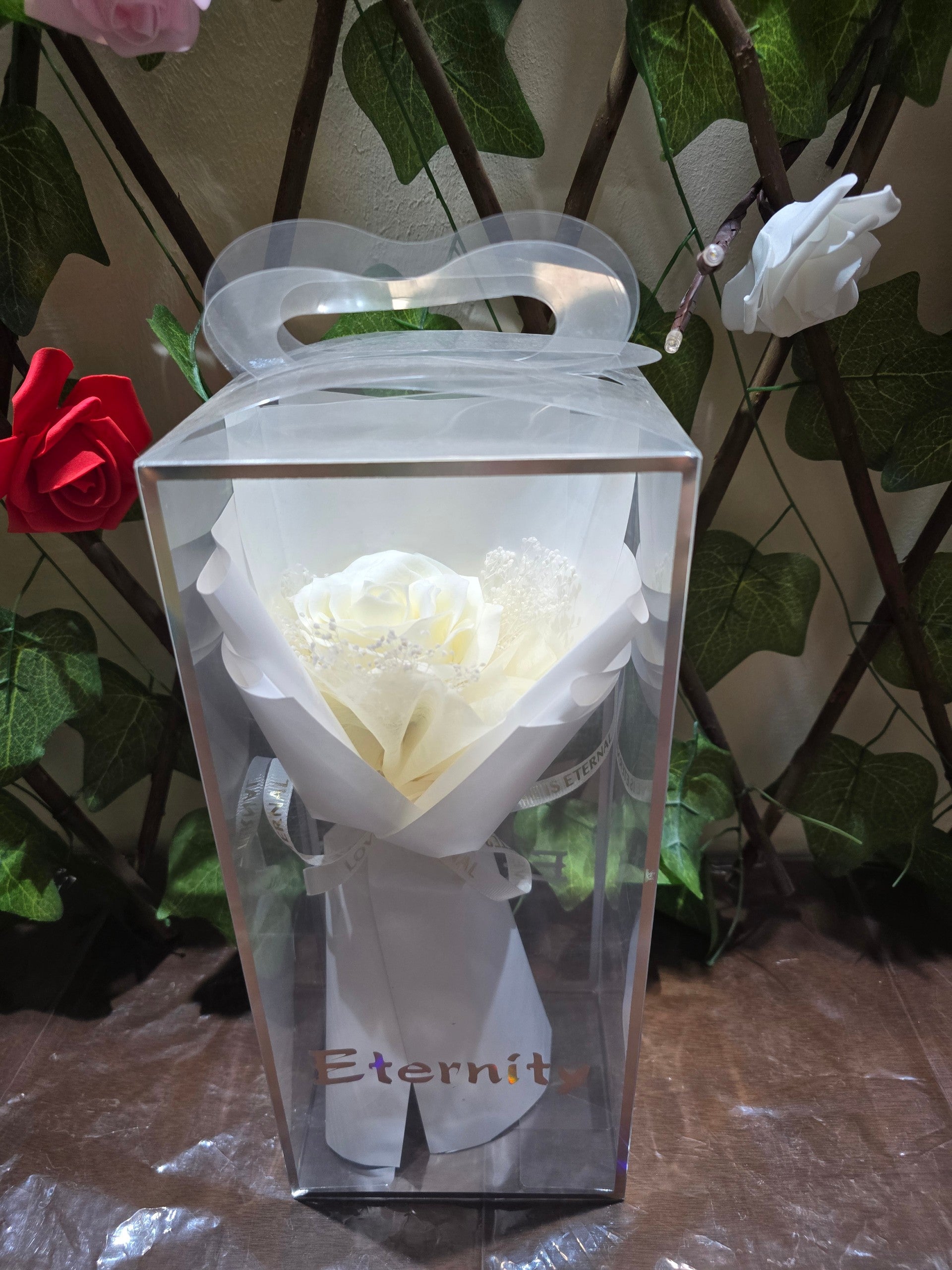 BioCode white artificial eternity rose bouquet in a clear presentation box with a ribbon and handle